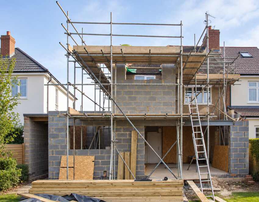 Two-storey home extension under construction with blockwork, timber and scaffolding